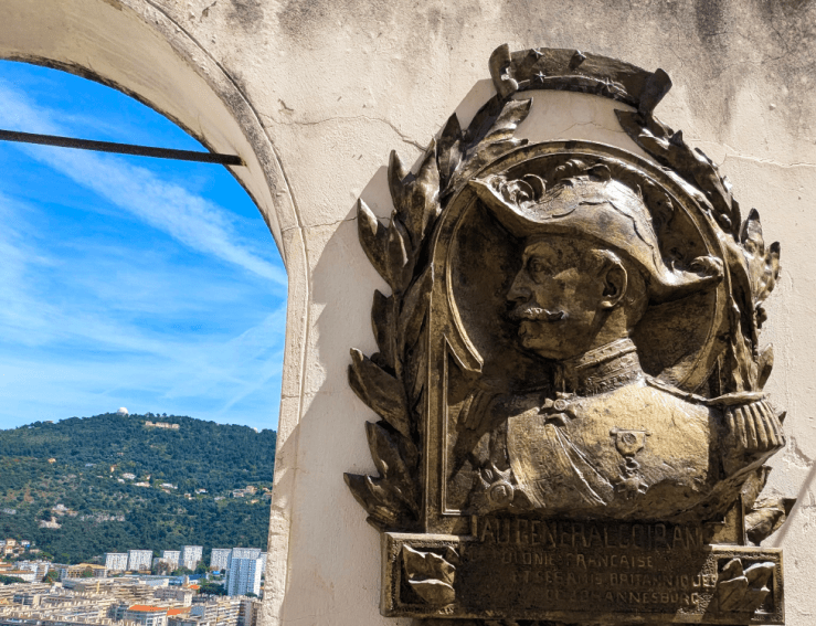 Bronze plaque of General Francois Louis Auguste Goiran, mounted on a wall with a view of the hills and sky in the background, located in Cimetiere de Cimiez, Nice.