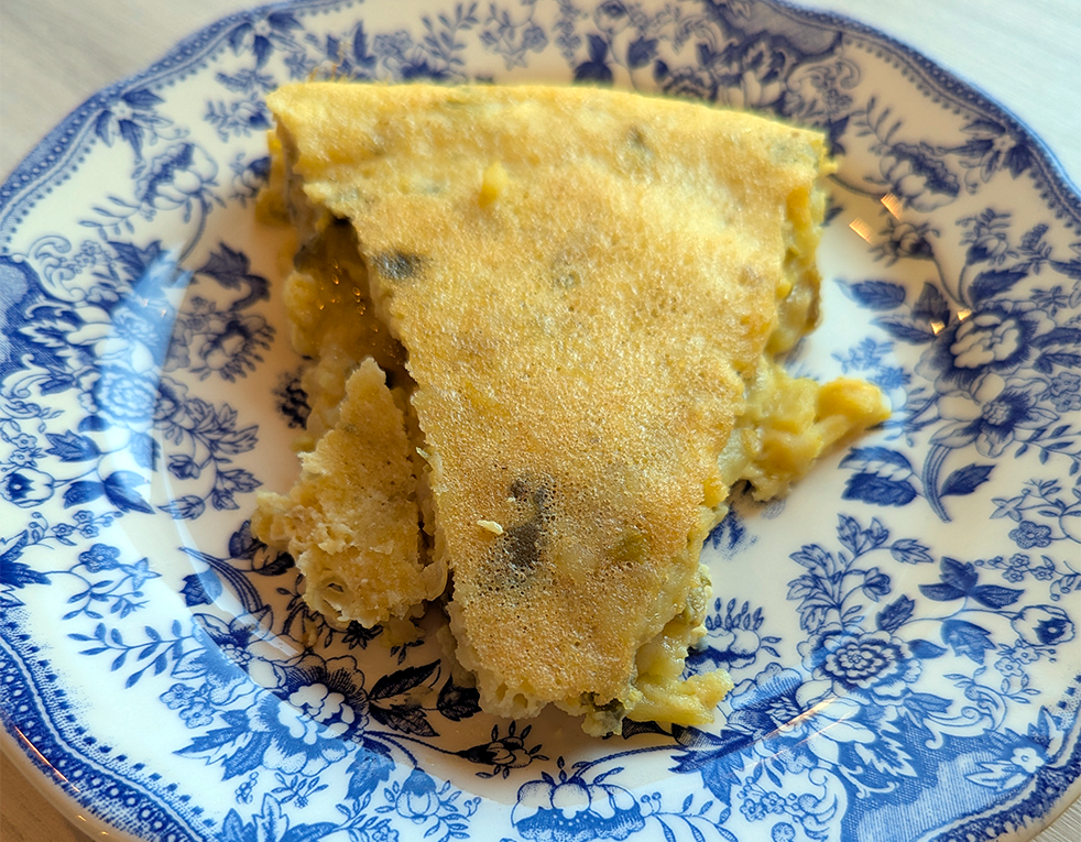 A slice of golden-brown savory pancake on a decorative blue and white floral plate.