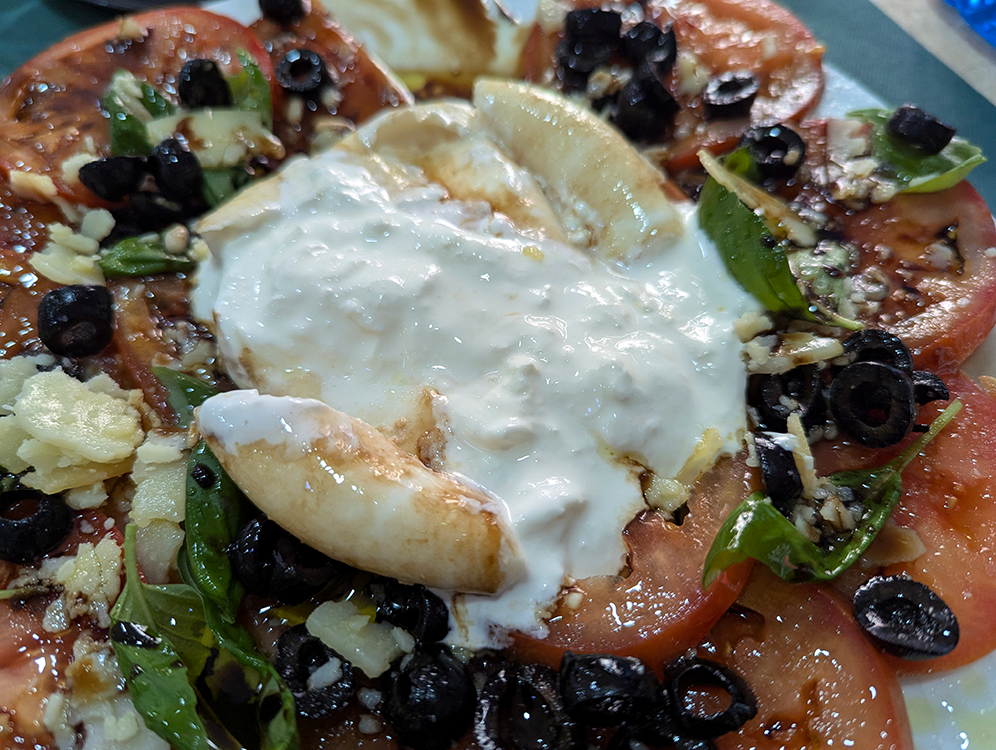 creamy burrata atop tomato salad at pizzeria la artesenal